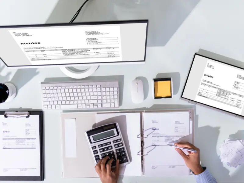 bookkeeping internet marketing Person managing invoices with computer and calculator.