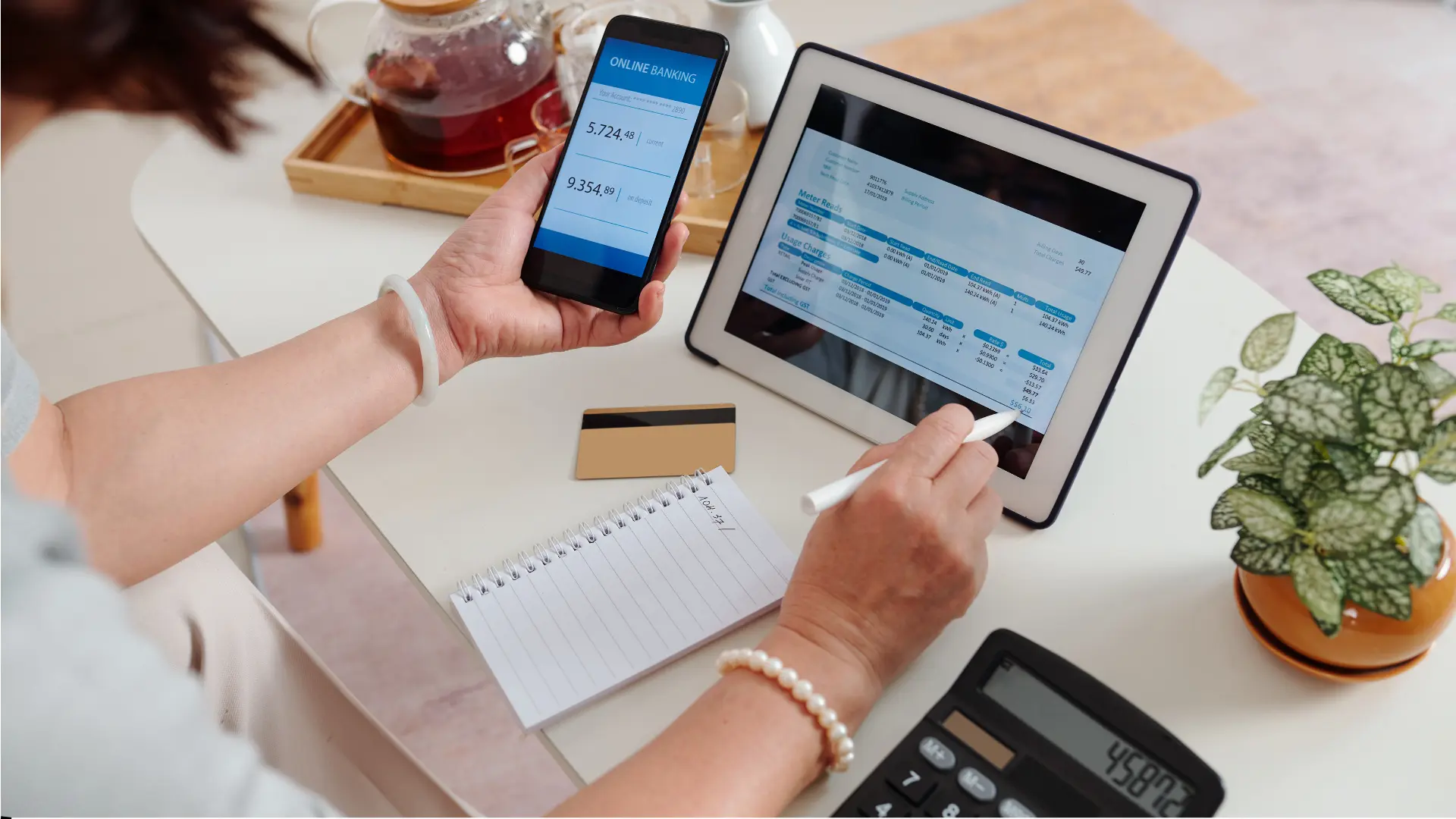 Person managing finances with phone, tablet, and calculator.