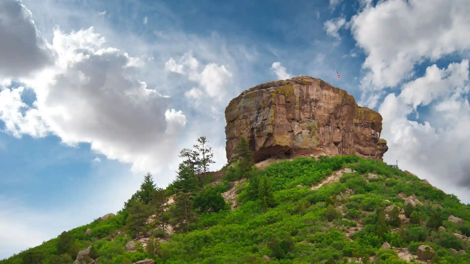 Green mountain with rocky summit under cloudy sky