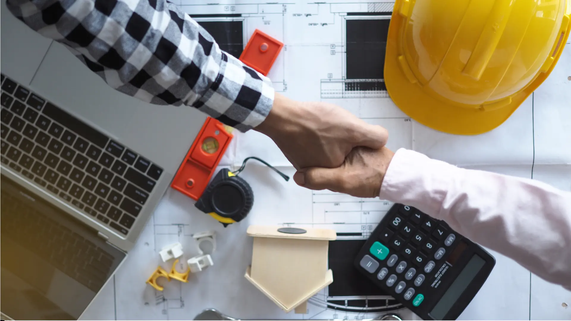 Construction handshake over blueprints and tools