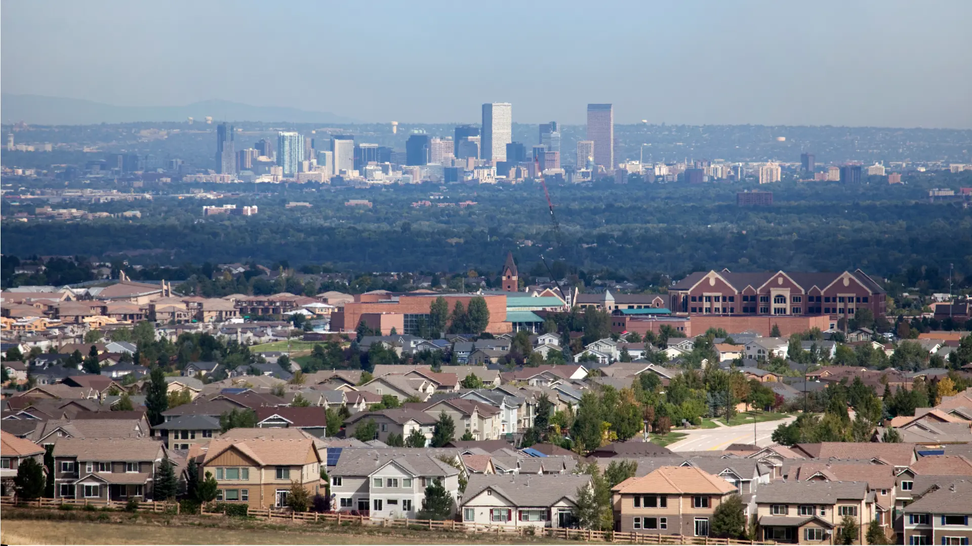 Suburban homes with city skyline in distance.