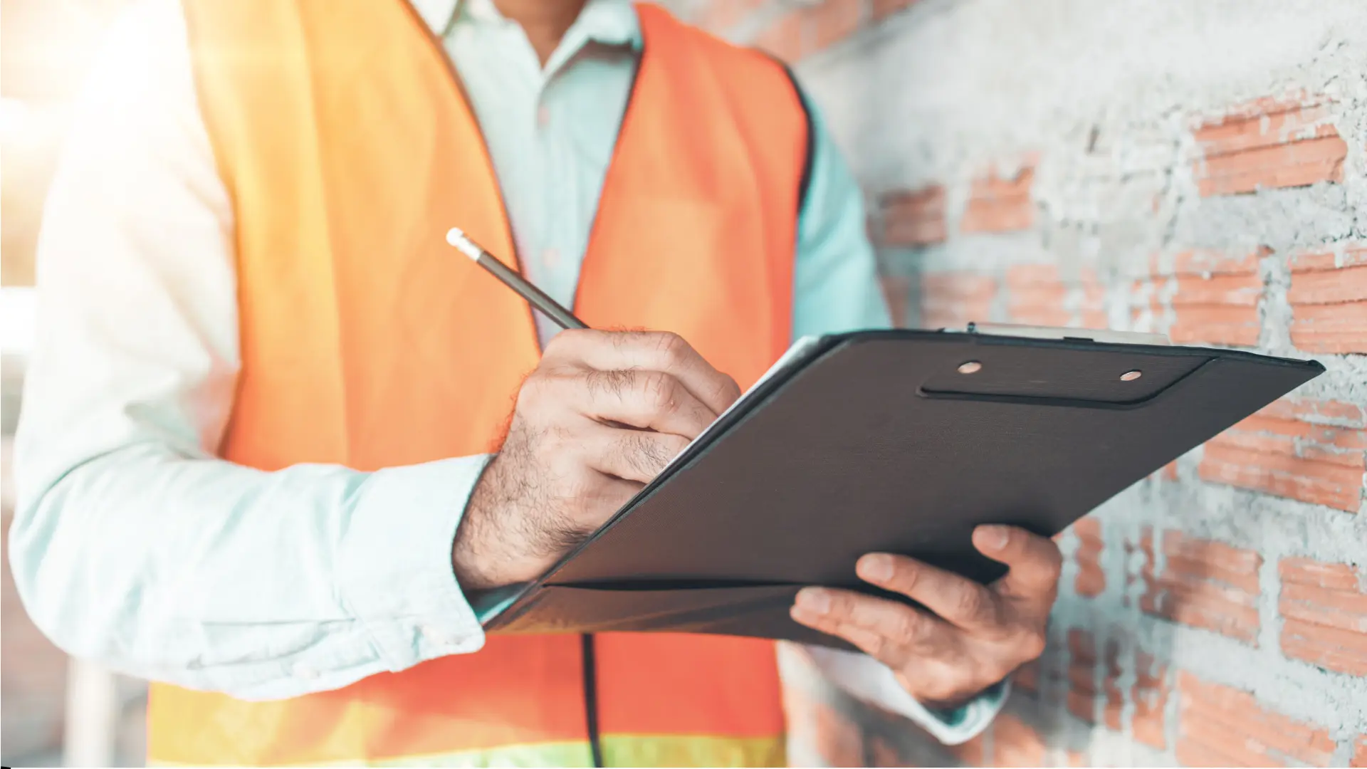 Construction worker writing on clipboard at site.