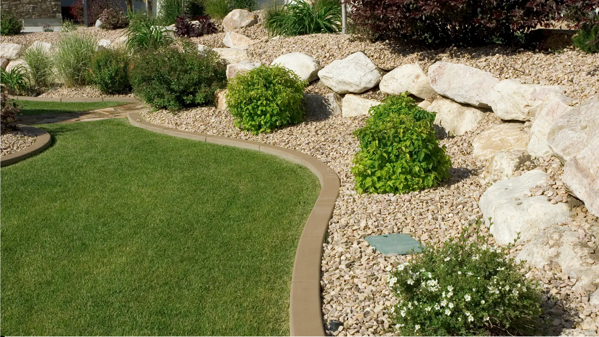 Landscape with grass, rocks, plants, and mulch border.
