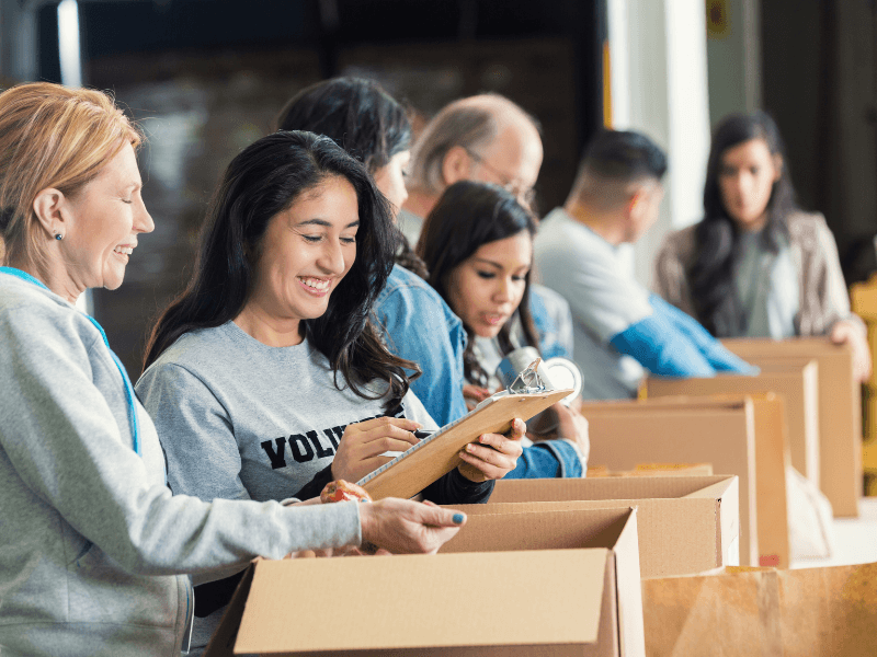 Volunteers organizing items in cardboard boxes.
