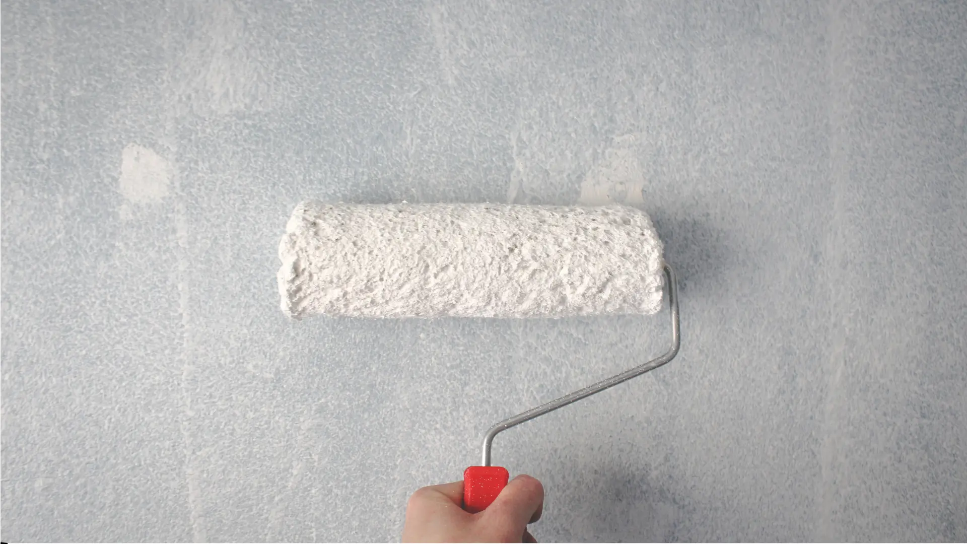 White paint roller used on gray wall