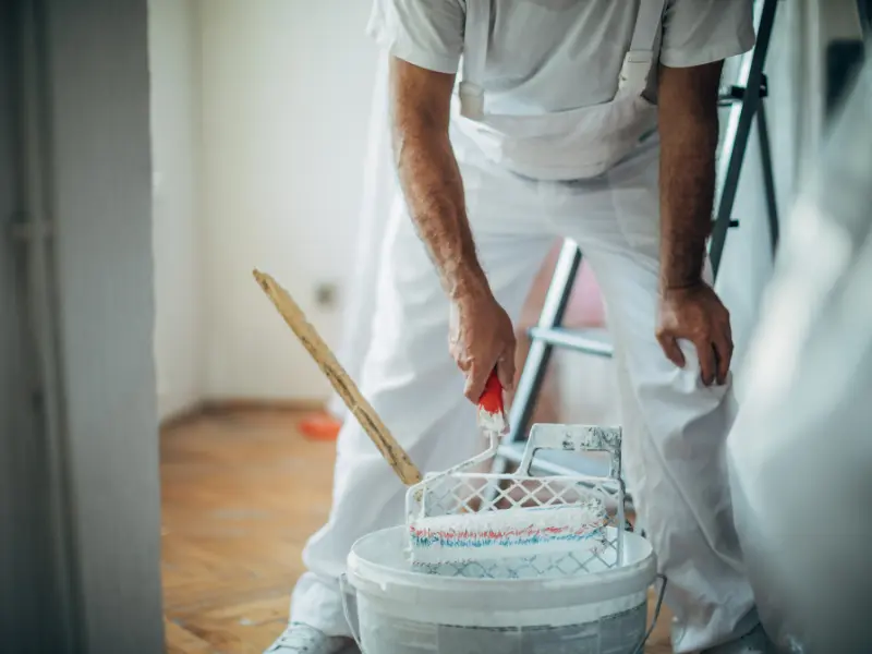Person painting interior wall with roller brush.