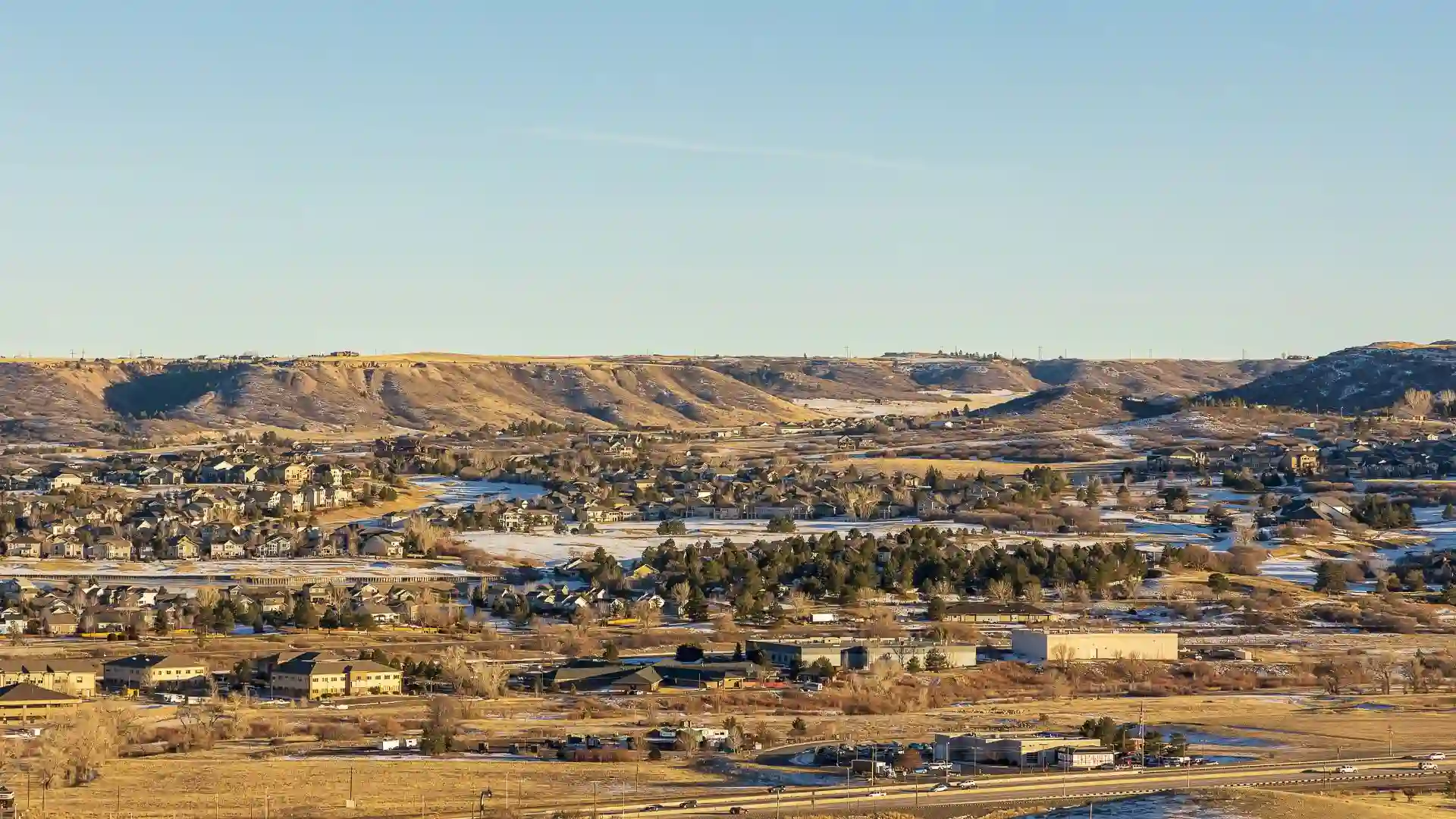 Suburban landscape with hills and houses at sunset.