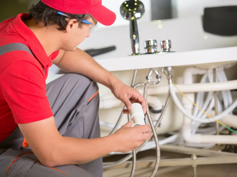 Plumber fixing bathtub pipes in bathroom