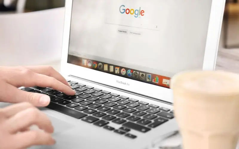 Person typing on laptop with Google homepage.